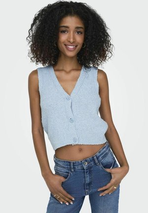 Top court bleu clair à encolure en V, texture tricotée et trois boutons à l'avant. Associé à un jean en denim bleu taille haute.