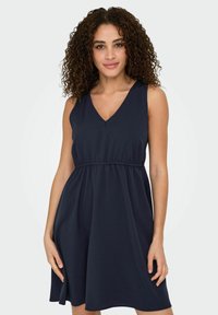 Marineblaue ärmellose Kleidung mit V-Ausschnitt, elastischem Bund und ausgestelltem Rock. Hergestellt aus glattem, leichtem Stoff. Minimalistisches Design.