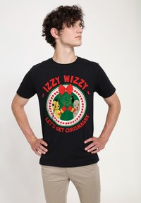 Sort t-shirt med et farverigt grafisk design featuring en grøn drage, gul hoved og rød sløjfe. Teksten lyder "IZZY WIZZY - LAD OS BLIVE JULENISSE."