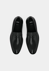 Mocassins en cuir noir au design élégant, texture lisse et détails de couture subtils. Dotés d'une semelle intérieure de marque et fabriqués en Italie.