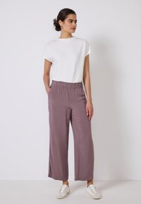 Bílý krátký rukáv top kombinovaný s volnými, mauve širokými kalhotami s elastickým pasem a dvěma předními kapsami. Nosit s bílými teniskami.