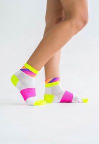 Helle, gemusterte Knöchelsocken mit weißen, neonpinken, grünen und orangefarbenen Streifen. Das Material wirkt leicht und hat strukturierte Mesh-Bereiche.