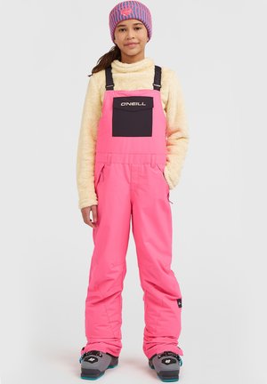 Roze sneeuwoverall met verstelbare banden, een zwarte voorkantzak en een zachte beige fleece top. De outfit is gecombineerd met sneeuwlaarzen en een gestreepte muts.