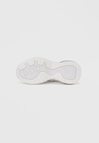 Λευκή σόλα αθλητικού παπουτσιού με υφή από καουτσούκ, διαθέτοντας πολυκατευθυντικά σχέδια πρόσφυσης και ελαφριά καμάρα για υποστήριξη.