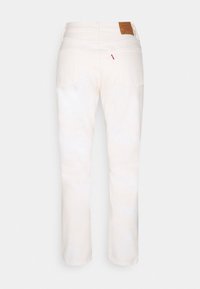 Jean blanc à jambes droites vus de dos avec deux poches, une étiquette de marque en cuir marron et une petite étiquette en tissu rouge.