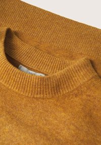 Musztardowo-żółty sweter z dzianiny z prążkowanym okrągłym dekoltem i miękką teksturą, prezentujący połączenie ciepłych i stonowanych odcieni.