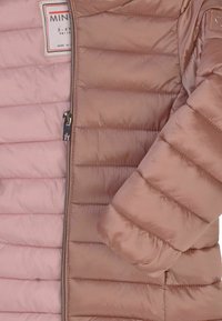 Giacca imbottita con una combinazione di colori rosa e rosa chiaro, dotata di zip, cuciture verticali e texture liscia. Etichetta visibile sul petto.