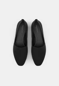 Pantofi negri tip slip-on cu vârf rotunjit, textură netedă și design minimalist. Au o siluetă cu tăietură joasă și branding subtil pe tălpicul interior.