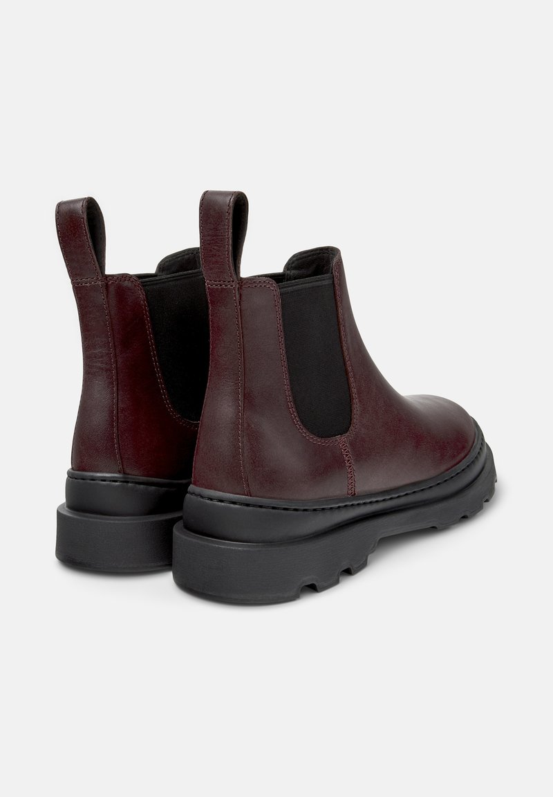 Burgundy leather Chelsea boots with black elastic inserts, pull tabs, and a thick black rubber sole. Smooth texture with stitching details.