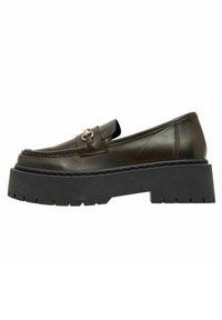 Bruine leren loafers met een dik zwart platformzool. Voorzien van decoratieve hardware op de wreef en gestikt detail langs de randen.