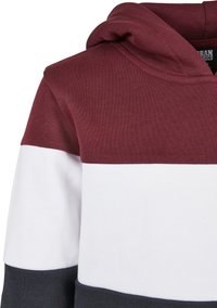 Felpa a blocchi di colore marrone e bianco con tessuto testurizzato, dotata di cappuccio e orlo contrastante grigio scuro sul bordo inferiore.