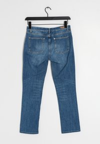 Jeans de mezclilla azul con un diseño de pierna recta, bolsillos traseros visibles y un ligero desgaste. La tela tiene una textura suave y un peso medio.