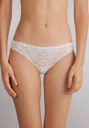 Witte kanten bikini ondergoed met een gegolfde tailleband en een hartenpatroon met fijne details. Zachte, delicate textuur.