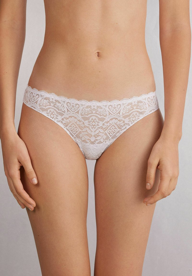 Witte kanten bikini ondergoed met een gegolfde tailleband en een hartenpatroon met fijne details. Zachte, delicate textuur.
