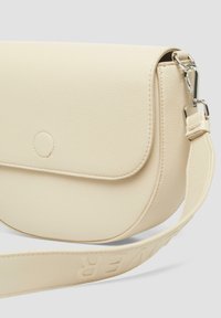Beige Leder-Crossbody-Tasche mit glatter Textur, magnetischem Klappenverschluss und verstellbarem Riemen mit geprägtem Schriftzug.