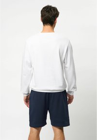 Witte lange mouwen shirt met een ronde hals, gladde textuur, gecombineerd met donkerblauwe shorts. Eenvoudig en casual ontwerp.