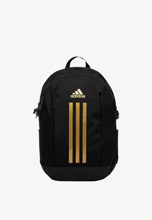 Zaino nero Adidas con logo dorato e tre strisce dorate verticali sul davanti, tasche con cerniera e maniglia superiore.