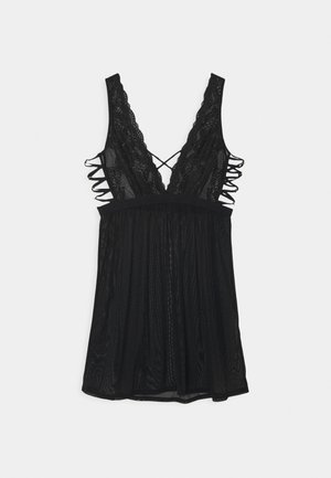 Zwarte kanten camisole met een diepe V-hals, verstelbare gekruiste schouderbanden en een textuur met gelaagde onderkant. Heeft geschulpt randen.