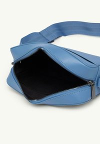 Niebieska skórzana torba z zamkiem błyskawicznym, o gładkiej teksturze, skośnym designie i mocnym materiałowym pasku. Wnętrze jest z czarnej tkaniny.