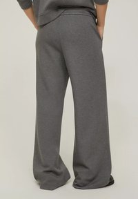 Pantaloni da jogging grigi a gamba larga realizzati in tessuto morbido, con vita elasticizzata e tasche laterali, caratterizzati da una superficie liscia e una vestibilità comoda.