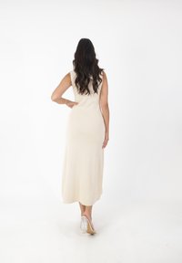 Beige ribbet strikket maxikjole med t�ætsiddende overdel, uden ærmer og en svajende nederdel. Sammen med klare hæle sandaler.