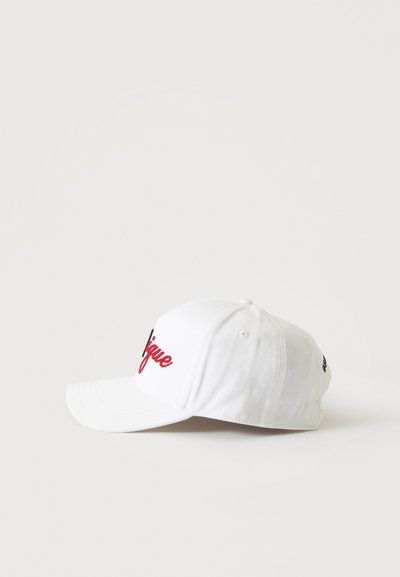 Casquette de baseball blanche avec des lettres cursives rouges et noires à l'avant, vue de profil sur un fond clair uni.