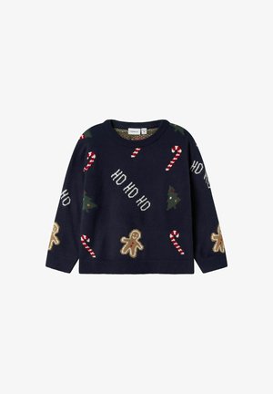 Marineblå strikkegenser med julemotiver: pepperkakemenn, sukkertøystokker, og juletre i grønt og rødt. Rund hals og lange ermer.