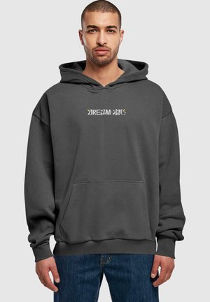 Grå hættetrøje med frontlomme, oversized pasform og "DRØM STORT" tekstdesign i kontrasterende farver. Blød stofsammensætning.