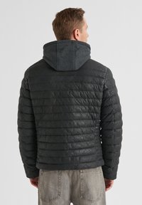 Schwarze Pufferjacke mit einer strukturierten Lederaußenseite und einer dunkelgrauen Kapuze. Verfügt über ein gestepptes Muster und gerippte Bündchen. Rückansicht gezeigt.