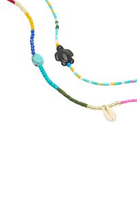 Kolorowy naszyjnik z koralików, zawierający turkusowe, zielone i różowe koraliki, z czarnym żółwiem i białymi muszlami akcentującymi, eksponujący różne tekstury i kształty.
