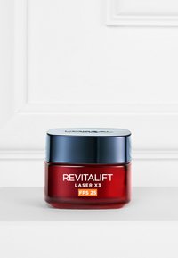 Bocal rouge avec une texture lisse et un couvercle bleu métallique. L'étiquette indique "REVITALIFT LASER X3 FPS 25" en police blanche et orange.