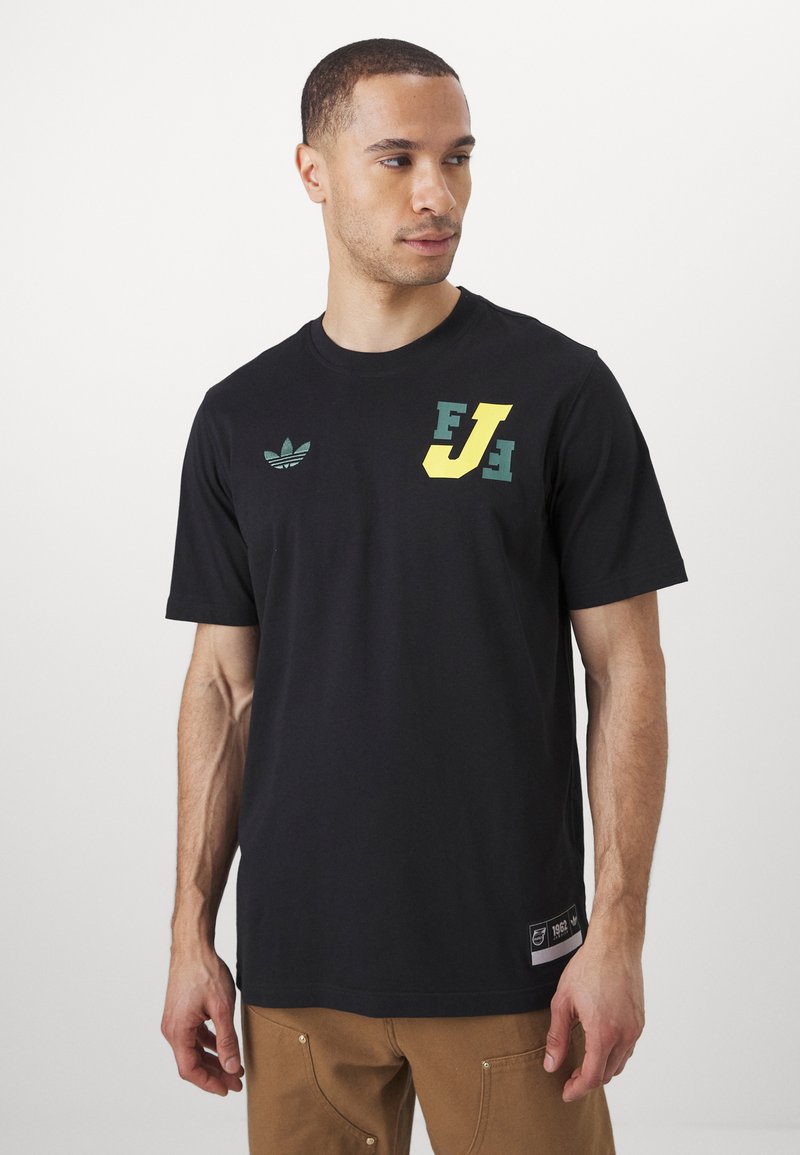 Black cotton t-shirt featuring green and yellow printed logos on the chest. Round neck, short sleeves, with a label on the bottom left side.