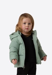 Mint green puffer jacket with a hood, quilted texture, front zipper, and side pockets, worn over a black garment by a child.