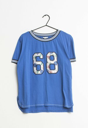 Blauw T-shirt met korte mouwen, witte en donkerblauw gestreepte kraag en boorden, met op de voorkant het nummer 68 in bloemmotief, hangend aan een zwarte hanger.