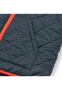 Giacca trapuntata di un blu navy scuro con cerniera e rifiniture arancioni brillanti. Presenta motivi diagonali e una tasca sul petto con cuciture a contrasto.