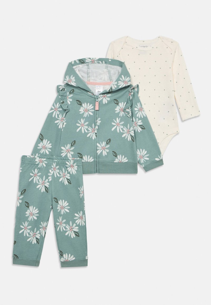 Completo per bebè a tre pezzi: giacca con zip a fiori verdi, pantaloni coordinati e body chiaro con pois. Tessuto in cotone, texture morbida.