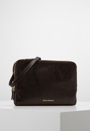 Brązowa, ciemnobrązowa skórzana saszetka na nadgarstek z złotymi zamkami, paskiem oraz złotym tłoczonym napisem "Royal Republic" na przodzie, umieszczona na białym tle.