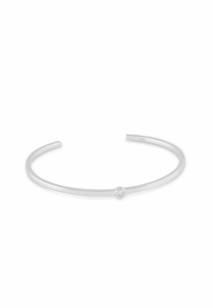 Bracciale rigido aperto in argento sottile con una piccola gemma rotonda trasparente al centro della fascia.