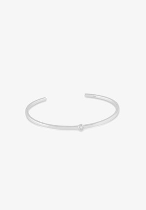 Dünnes, silbernes offenes Manschettenarmband mit einem kleinen, runden, klaren Edelstein in der Mitte des Bandes.