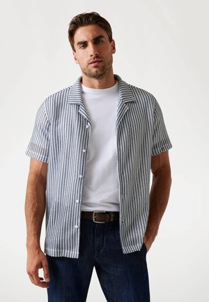 Chemise à manches courtes, avec col, présentant un motif géométrique bleu et blanc, fabriquée en tissu texturé ; dotée d'un devant à boutons et d'une poche poitrine.