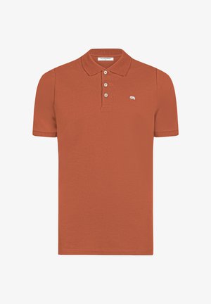 Ruosteenvärinen lyhythihainen poolopaita, jossa on kolme nappia ja vasemmassa rinnassa pieni valkoinen karhulogo.