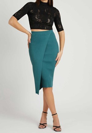 Türkis gerippter Bleistiftrock mit asymmetrischem Frontsaum, kombiniert mit einem schwarzen, spitzenbesetzten Crop-Top und schwarzen, Riemchen-Sandalen.