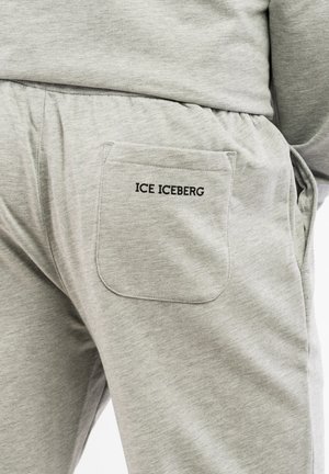 Sive trenerke iz teksturiranega materiala, z zadnjim žepom, na katerem je črn vezen napis "ICE ICEBERG". Podrobnost elastičnega pasu.