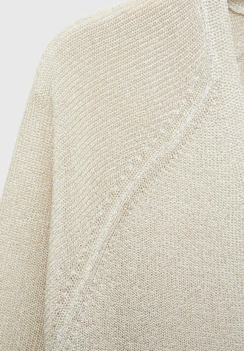 Beżowy sweter z dzianiny o teksturowanym wzorze, charakteryzujący się luźnym krojem i szerokim kołnierzem. Miękka, lekka tkanina.