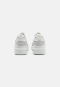 Hvite sneakers med en kombinasjon av glatt lær og semsket skinn. Tykk hvit såle med "BOGNER" preget på hælen. Mesh-detaljering bak.
