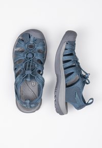 Blue outdoor sandals with a textured grey sole, featuring woven straps, adjustable laces, and a cushioned insole for comfort.