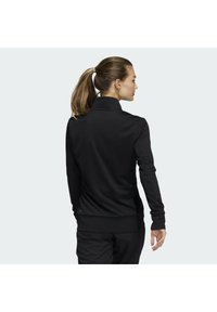 Schwarzer Pullover aus glattem Material, mit hohem Kragen und gerippten Bündchen, in einer taillierten Passform, die einen klaren und modernen Look bietet.