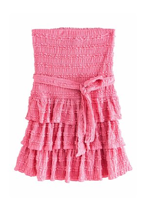 Rozā daudzslāņu kleita, izgatavota no teksturēta auduma. Tai ir gurniem pieguloša virsdaļa un saitīte jostai. Dizains ietver volānu slāņus un frēgo apakšmalu.