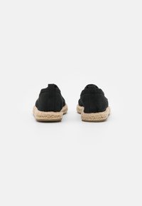 Svarta espadrilles med ett textilöverdrag och vävd jutesula. Har en låg profil och en bakre flik för enkel påtagning. Slät textur.