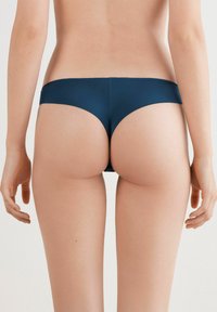 Granatowe bikini dolne wykonane z gładkiego, elastycznego materiału, charakteryzujące się niskim stanem i bezszwowym designem z minimalnym zakryciem z tyłu.